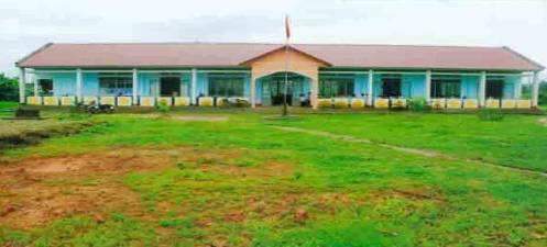 A one-story building with a red roof and light blue walls, featuring a central entrance and surrounded by green grass.