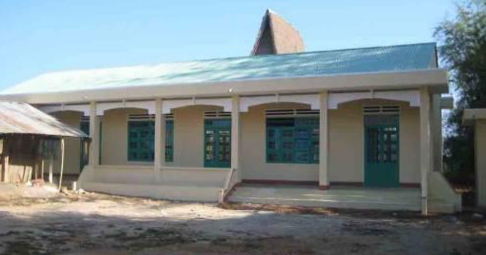 A single-story building with a green roof and multiple teal doors and windows under a clear blue sky.A single-story building with a green roof and multiple teal doors and windows under a clear blue sky.