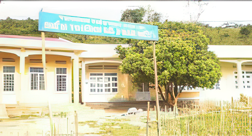 A building with a signboard in an outdoor setting surrounded by greenery. The building appears to be a public facility.