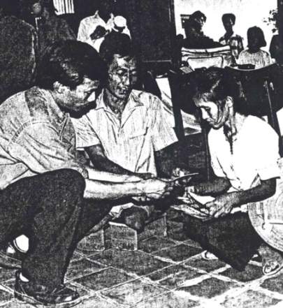 Ca Van Tran (I) at the rehabilitation clinic in Can Tho with a vetran of the South Vietnamese Army (ARVN who lost both legs during the war. Having neither artificial legs nor a wheelchair, the man must use  the wooden block on which he is sitting as "hand crutches."